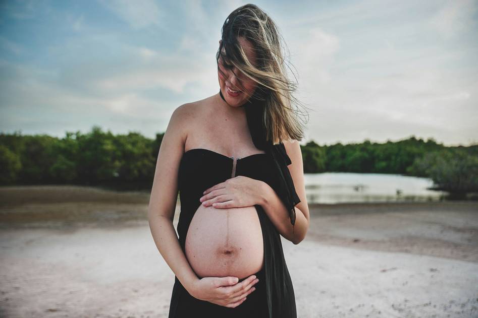 Pregnant woman holding prenatal vitamin bottle in soft natural light